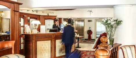 A reception area with a wooden reception desk, a clock, and a reception sign.