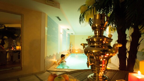 Un espace de bien-être avec une piscine, une lampe décorative et des bougies.