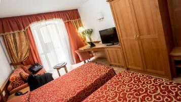 Ett hotellrum med två sängar, ett skrivbord med en dator, en tv och en garderob.