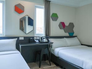 A hotel room with two beds, a desk, a chair, and a window with curtains.