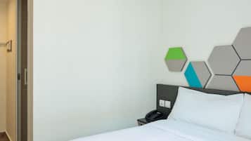 A hotel room with a bed, a nightstand with a phone, and a wall with geometric wall art.