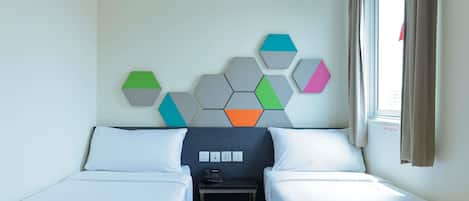 Habitación de hotel con dos camas, una mesita pequeña y una obra de arte geométrica colgada en la pared.