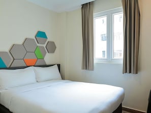 A hotel room with a bed, a window with curtains, and a wall with a geometric pattern. - ibis budget Singapore Jasmine (Singapore)
