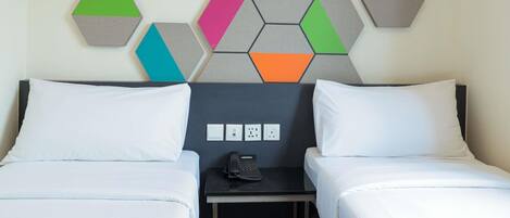 Habitación de hotel con dos camas, una mesita de noche y un teléfono instalado en la pared.