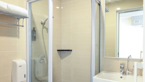 A modern bathroom with a glass-enclosed shower, a white sink, and a hand dryer.