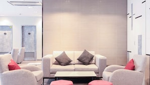 A modern lobby with a sofa set, two ottomans, and a wall with lockers.