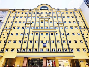 Un bâtiment jaune avec de nombreuses fenêtres et une enseigne indiquant « Ibis Budget Hotel ».