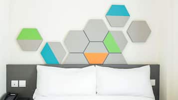 A hotel room with a bed, a nightstand, a phone, and a wall with hexagonal wall art.