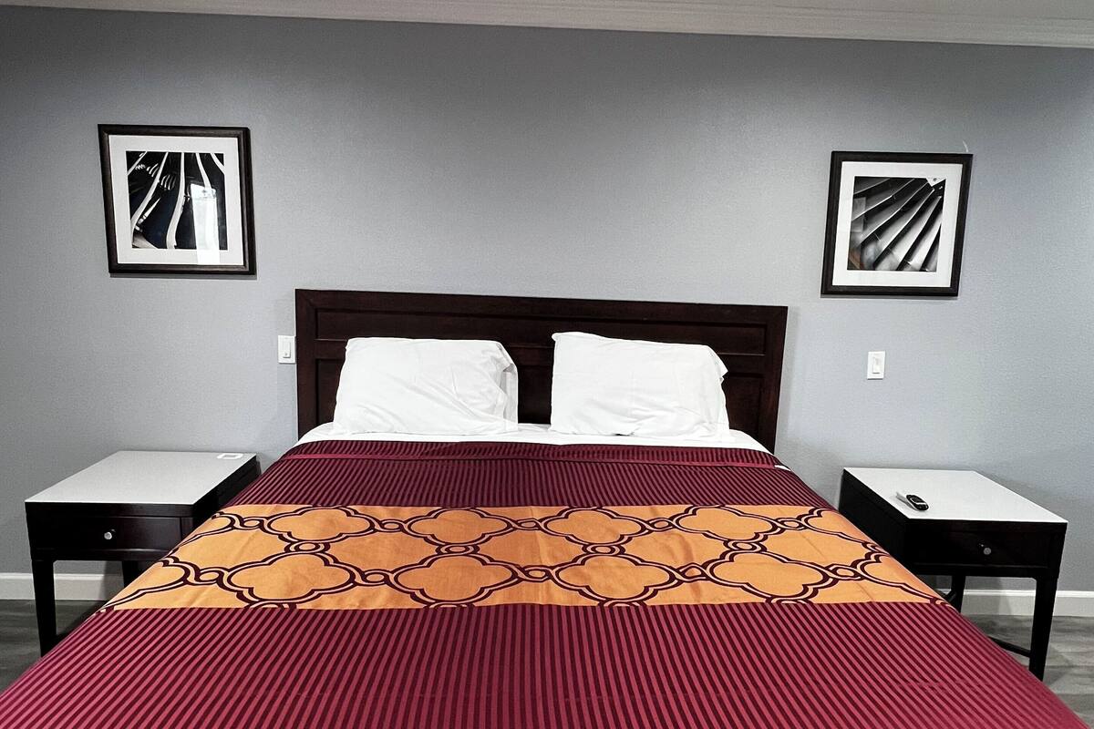 A hotel room with a large bed, two nightstands, and two framed pictures on the walls.