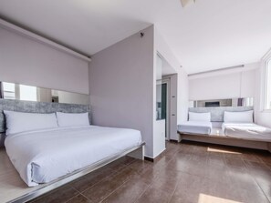 Een moderne hotelkamer met een groot bed, een kleiner bed en een inloopkast.