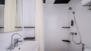 Un baño moderno con lavamanos, espejo y ducha blancos.