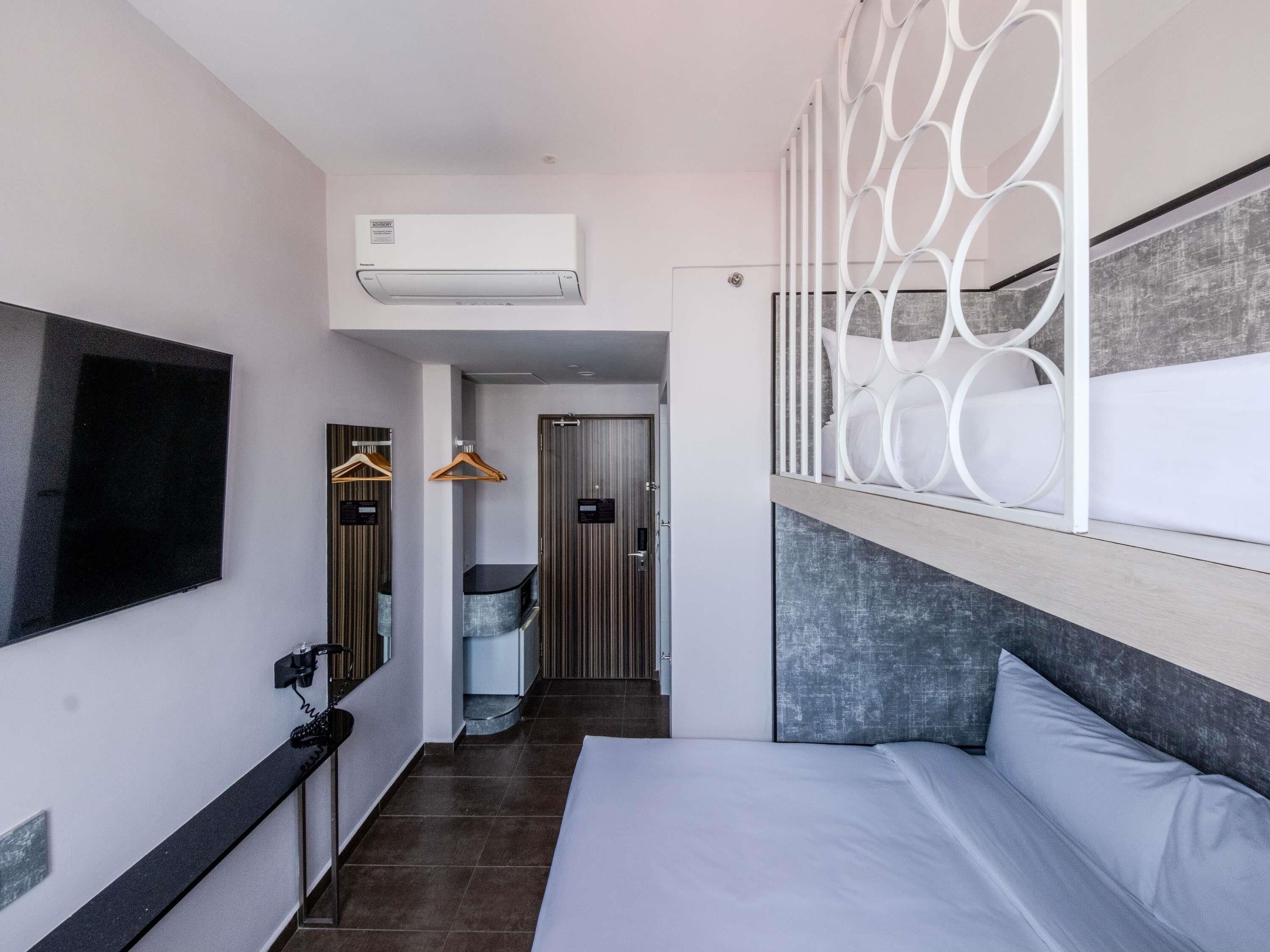 Une chambre d’hôtel avec un lit, une télévision, une salle de bain et un couloir.