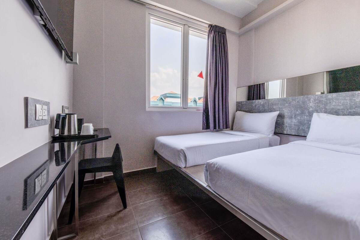 Een hotelkamer met twee bedden, een bureau en een stoel.