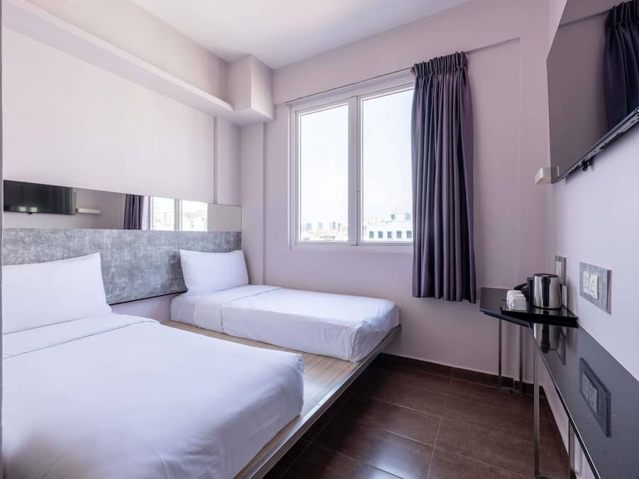 Habitación de hotel con dos camas, ventana con cortinas, televisión de pantalla plana, cafetera y estante de pared.