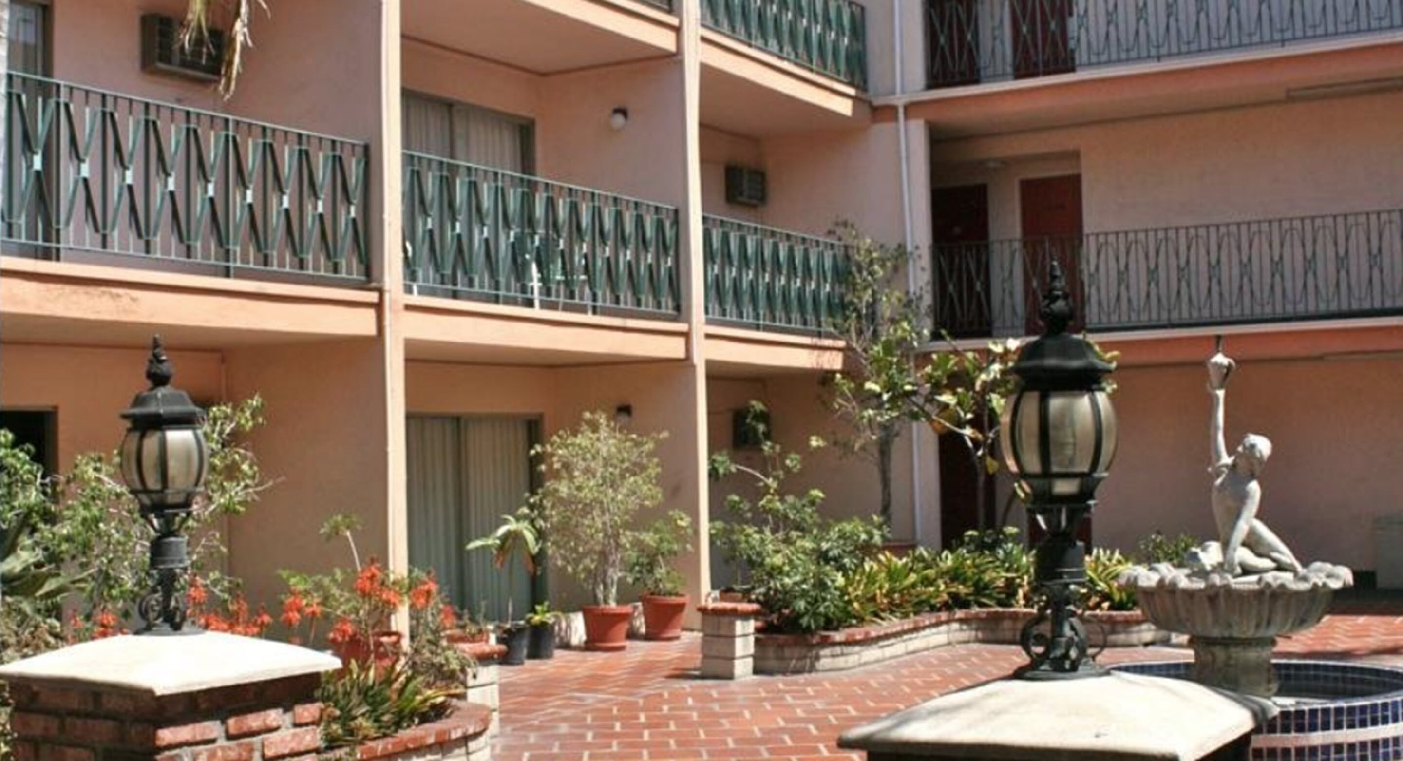 A multi-level building with balconies, potted plants, and a fountain.