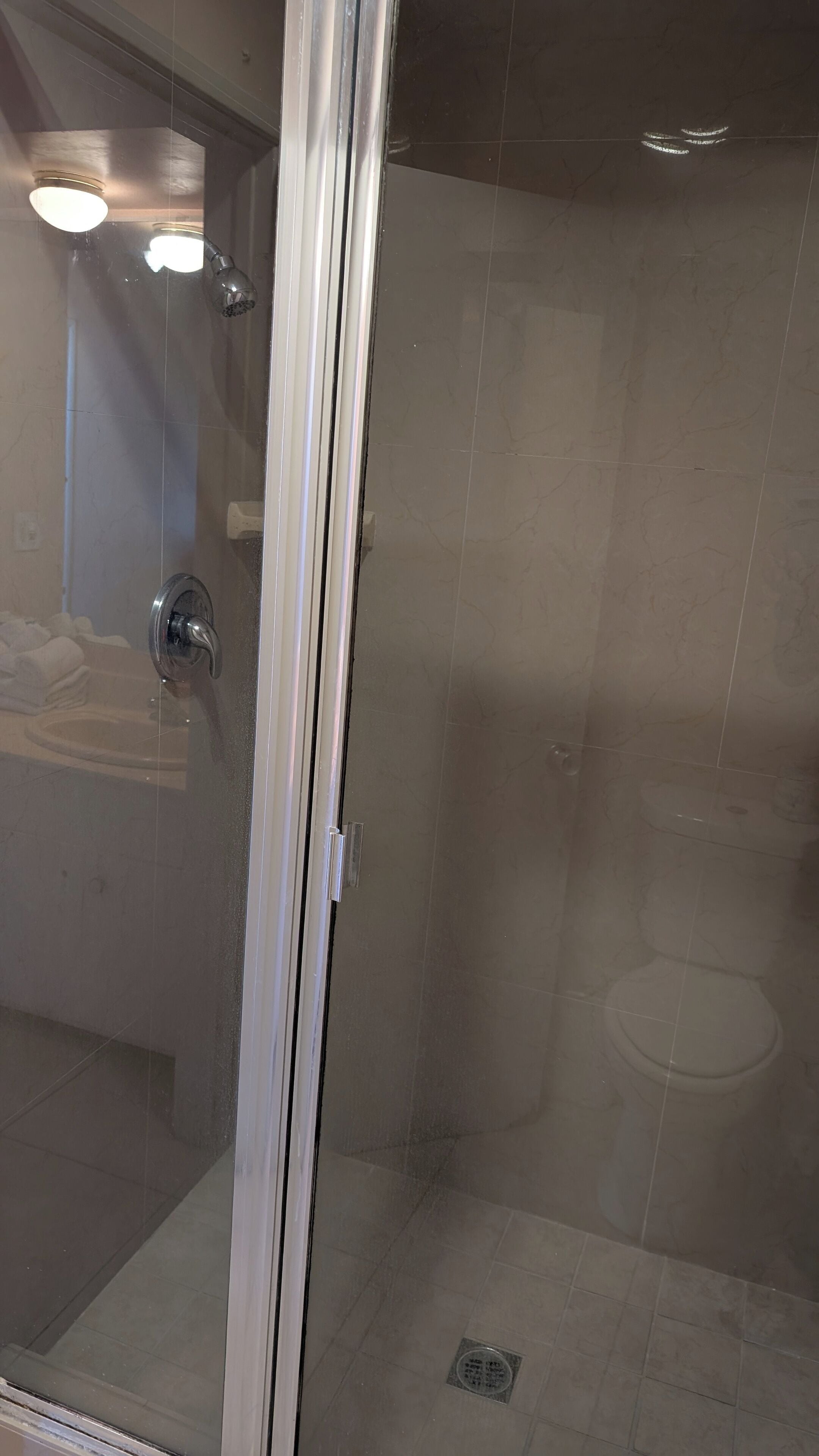 Un baño con cabina de ducha de vidrio, inodoro y lavabo.