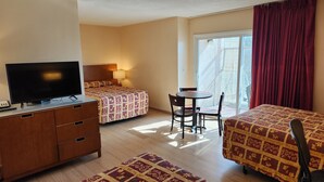 A hotel room with two beds, a TV, a desk, and a chair.