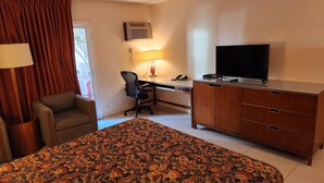 A hotel room with a bed, a desk, a chair, a television, and a wardrobe.