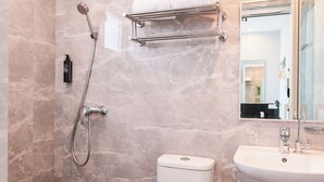 A bathroom with a shower, toilet, sink, and a towel rack. - ibis budget Singapore Tulip (Singapore)