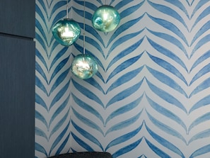 Una habitación con papel tapiz estampado y tres lámparas esféricas colgantes.