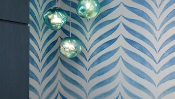 Una habitación con papel tapiz estampado y tres lámparas esféricas colgantes.