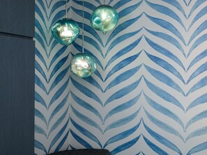 Una habitación con papel tapiz estampado y tres lámparas esféricas colgantes.