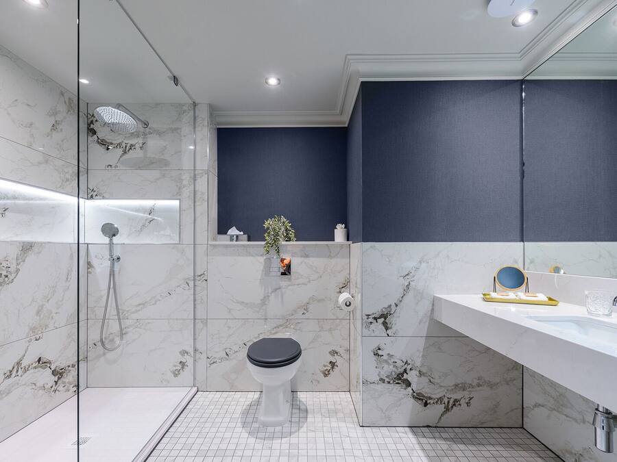 A modern bathroom with a glass-enclosed shower, a toilet, and a vanity with a mirror.