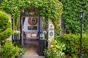 A hotel entrance with a black door, a round mirror, and a sign indicating the year 2023. - The Victoria (Killarney)