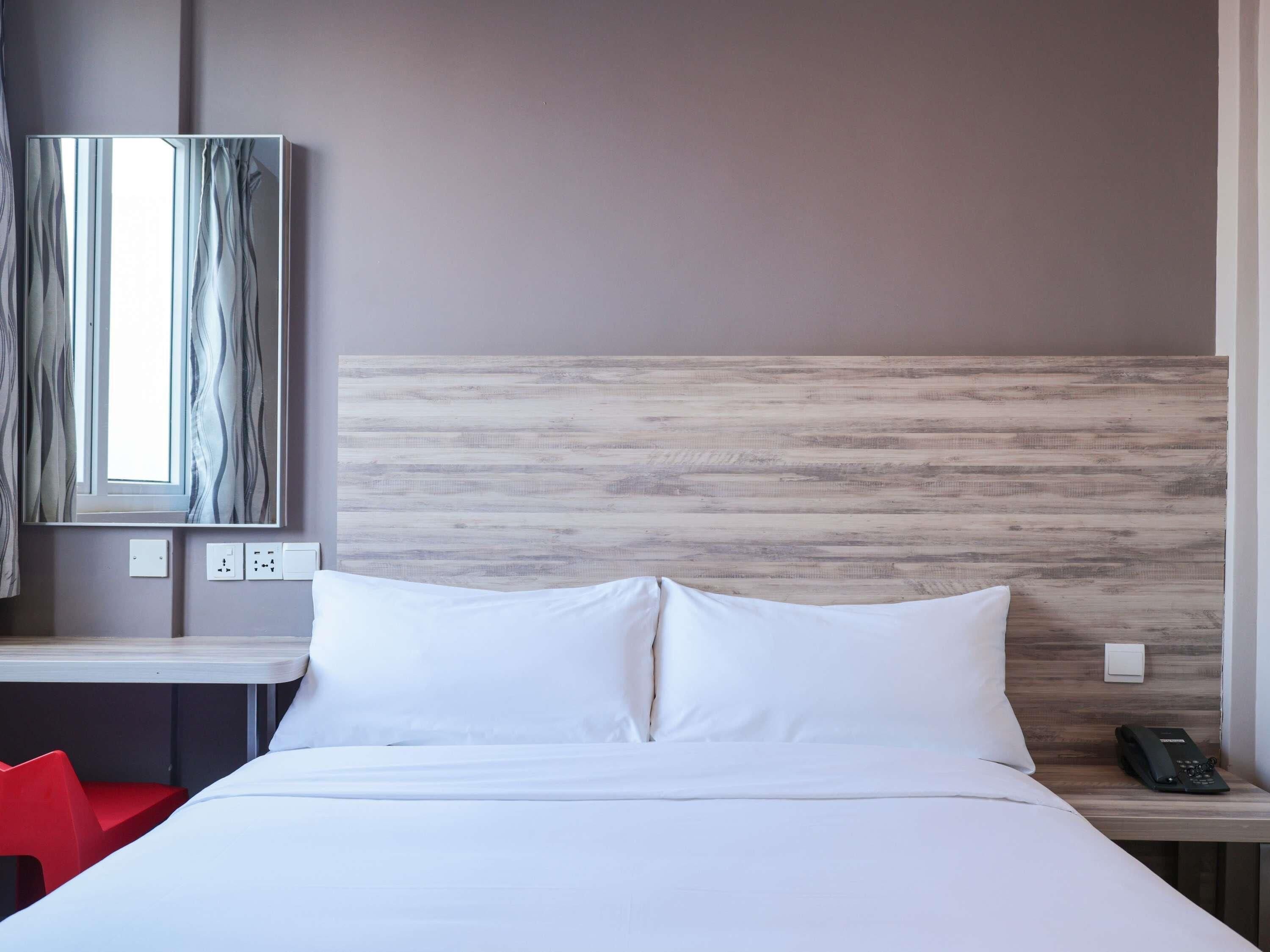 Habitación de hotel con cama, escritorio, silla, teléfono e interruptor de luz en la pared.