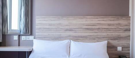 Habitación de hotel con cama, escritorio, silla, teléfono e interruptor de luz en la pared.