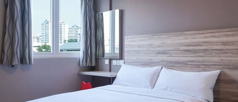 A hotel room with a bed, a nightstand, a mirror, and a window with curtains.