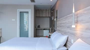 Habitación de hotel moderna con una cama grande, un escritorio, un espejo y vistas a edificios a través de la ventana.