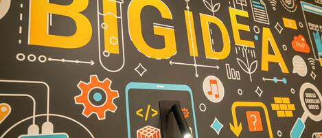 A wall with the words "BIG IDEA" and various icons like a light bulb, gears, and a mobile phone.
