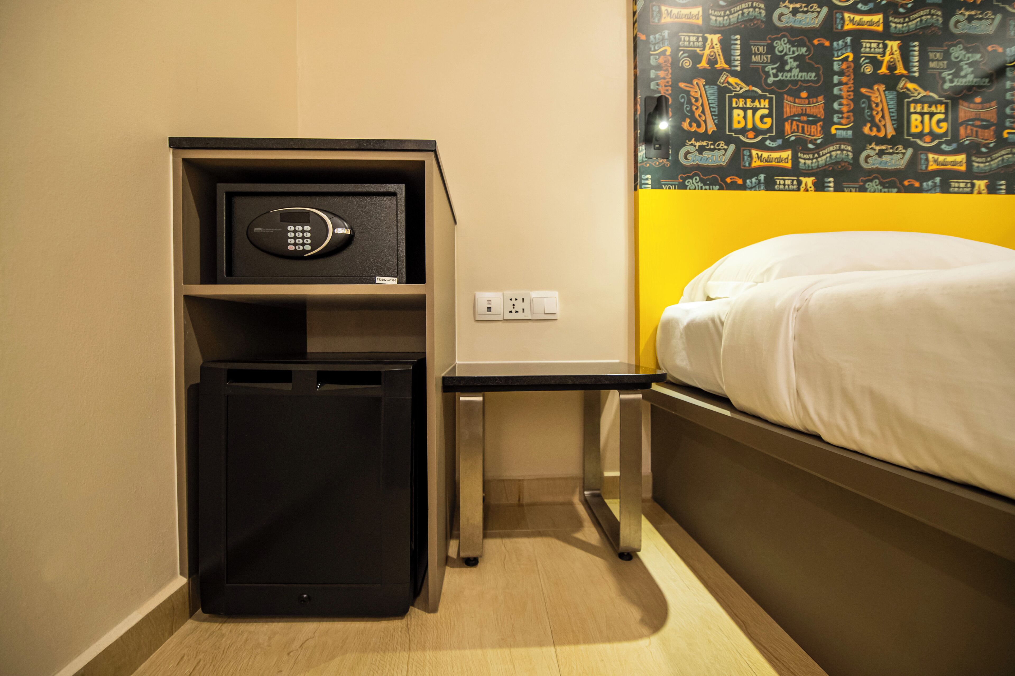 Habitació d'hotel amb un llit, una caixa forta petita i una tauleta de nit.