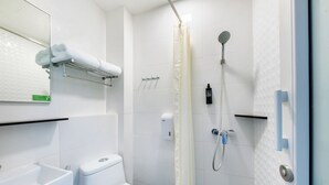 Un baño moderno con inodoro, lavamanos, ducha y un perchero para toallas.