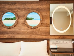 A hotel room with a wooden headboard, two round mirrors with beach views, a bedside table with a hairdryer, and a power outlet. - ibis budget Singapore Selegie (Singapore)