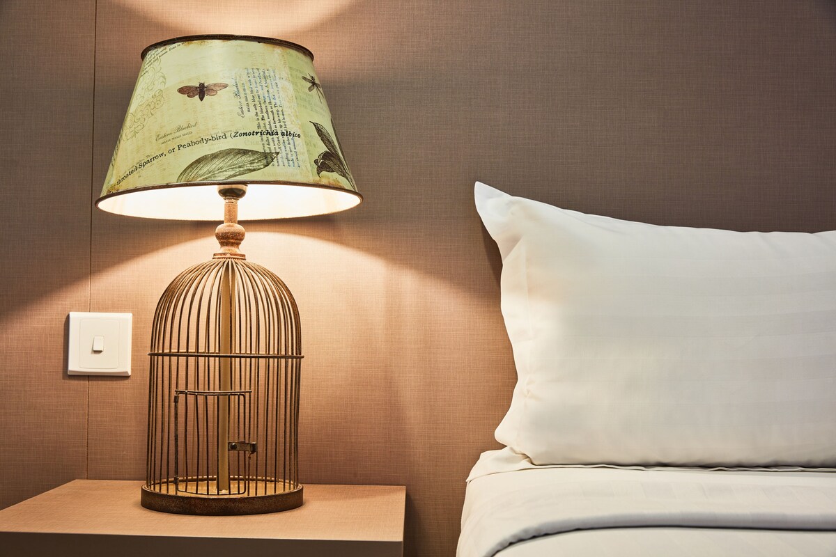 A lamp with a vintage design on a bedside table next to a bed.
