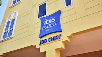 Letrero de hotel con 'ibis budget' y 'JOO CHAT' en la fachada de un edificio amarillo.
