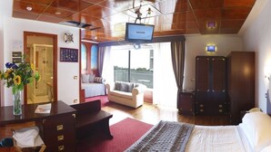 A hotel room with a bed, a desk, a chair, a sofa, a TV, and a balcony with a view. - Hotel Soraya (Lignano Sabbiadoro)