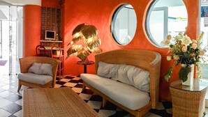 A room with wicker furniture, a checkered floor, and a large window. - Hotel Soraya (Lignano Sabbiadoro)