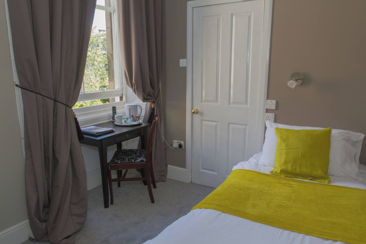 A bedroom with a bed, a desk, and a chair.
