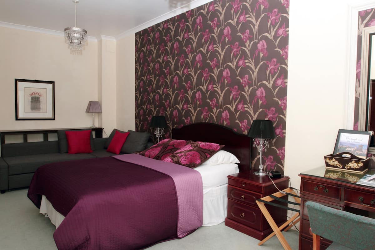 A bedroom with a bed, a dresser, a nightstand, a lamp, and a framed picture on the wall.