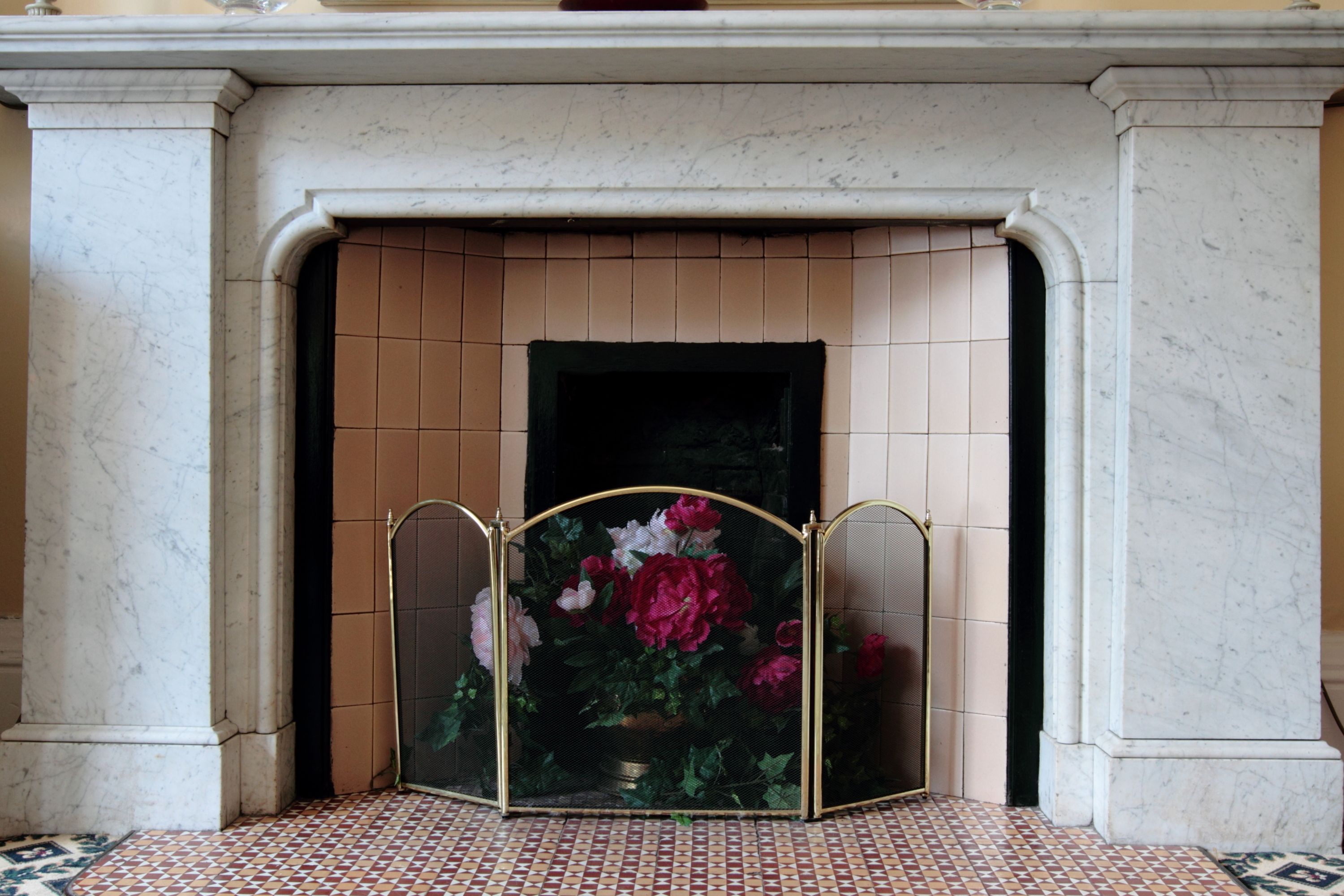A fireplace with a tiled surround and a decorative screen.