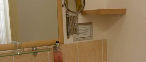 Un baño con lavabo, espejo, toallero y un cuadro en la pared.