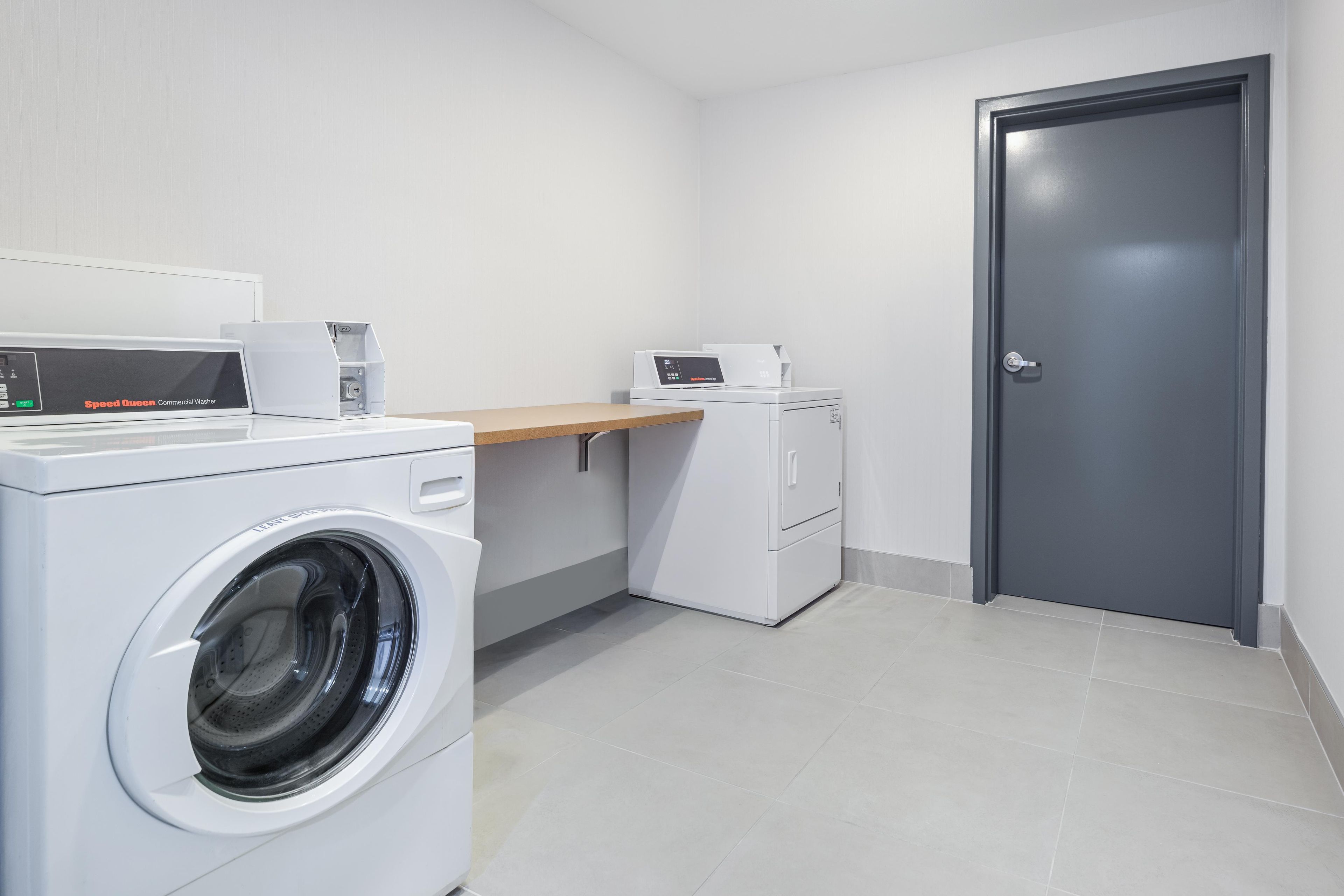 A laundry room with a front-loading washing machine, a dryer, and a small countertop with a coffee maker.