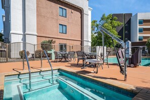 A pool area with a diving board, lounge chairs, and a building in the background. - Hampton Inn & Suites Oakland Airport-Alameda (Alameda)