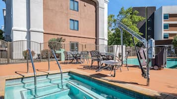 Área de piscina com trampolim, espreguiçadeiras e um edifício ao fundo.
