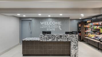 Una recepción con un letrero que dice 'Welcome to the Golden State', un minibar y un bar de aperitivos con diversos productos alimenticios.