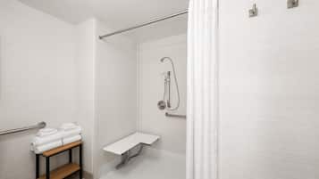 A modern bathroom with a shower, a towel rack, and a small shelf.