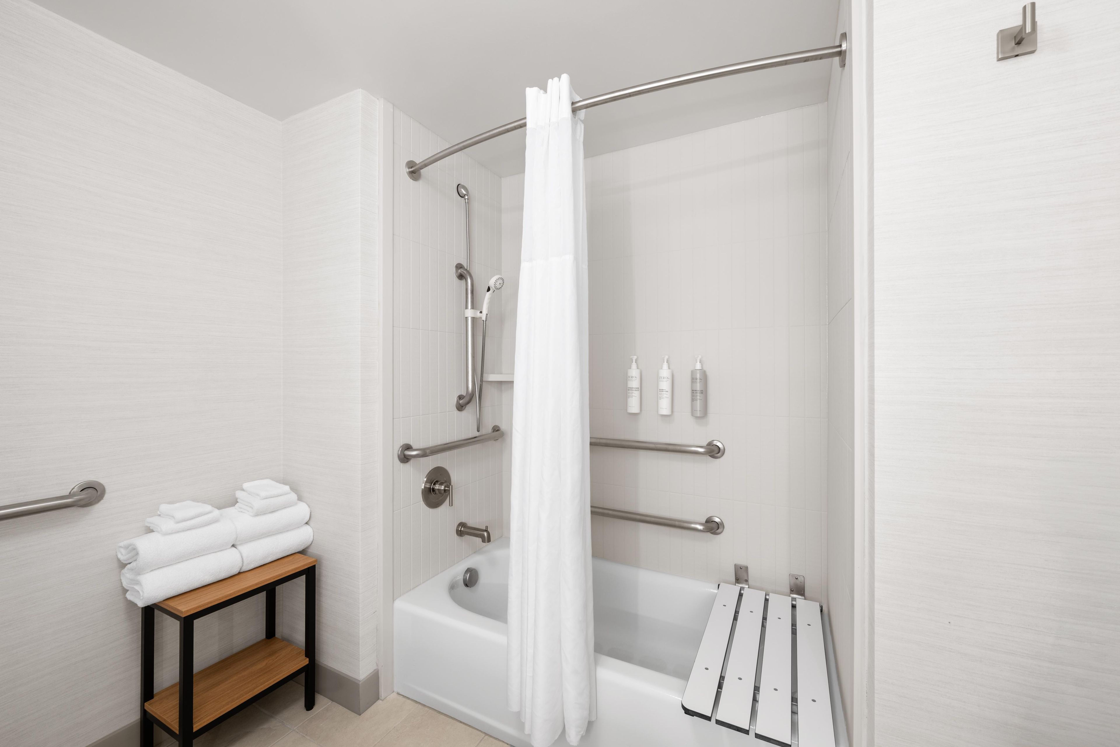Ein modernes Badezimmer mit Dusche, Badewanne und Handtuchhalter.